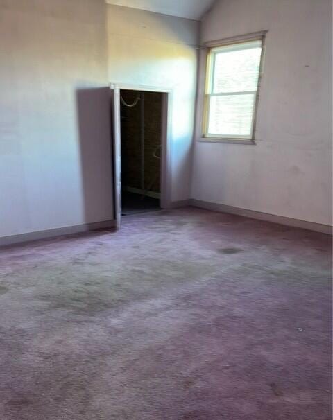 unfurnished bedroom featuring carpet and vaulted ceiling