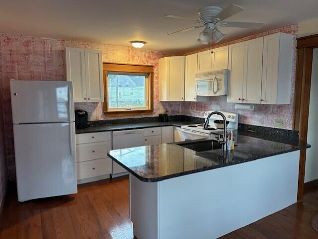 kitchen featuring white cabinetry, kitchen peninsula, dark hardwood / wood-style flooring, sink, and white appliances