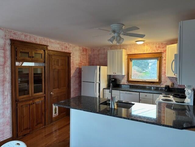 kitchen featuring dark hardwood / wood-style flooring, white cabinets, kitchen peninsula, sink, and appliances with stainless steel finishes