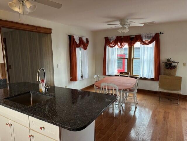 kitchen with white cabinets, sink, dark hardwood / wood-style floors, ceiling fan, and dark stone countertops