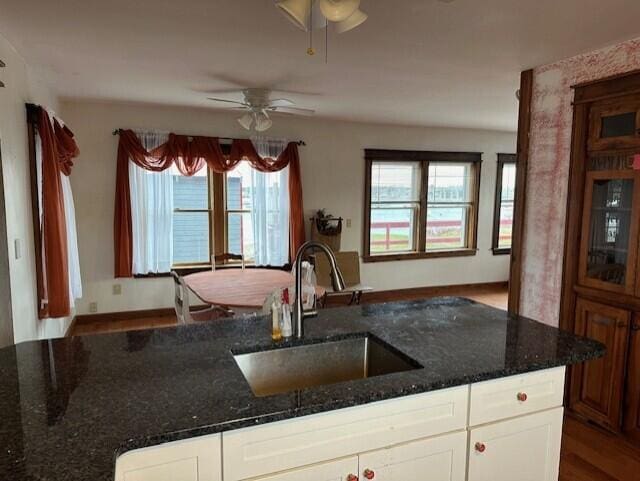 kitchen with dark stone counters, white cabinetry, dark hardwood / wood-style flooring, sink, and ceiling fan