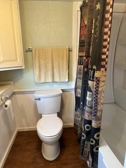 bathroom with wood-type flooring, shower / bathtub combination with curtain, and toilet