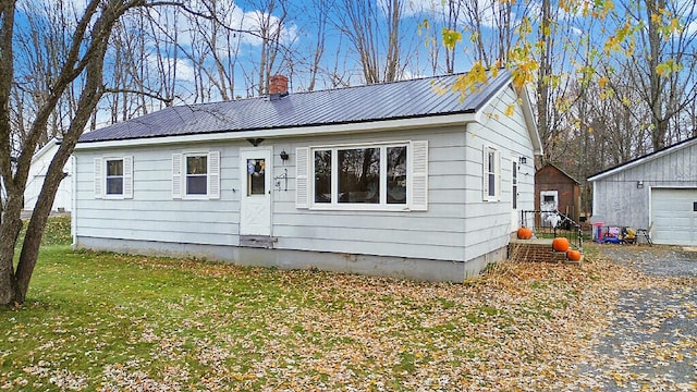 view of front of house with a garage, an outdoor structure, and a front yard