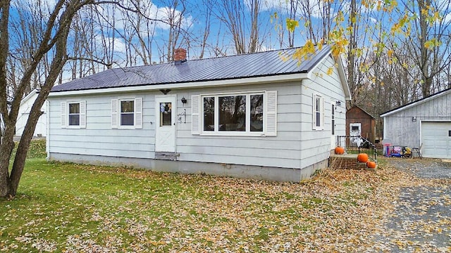 18 Sebasticook Dr, Clinton, ME 04927 - view of front facade featuring a chimney, metal roof, an outbuilding, a front yard, and a garage