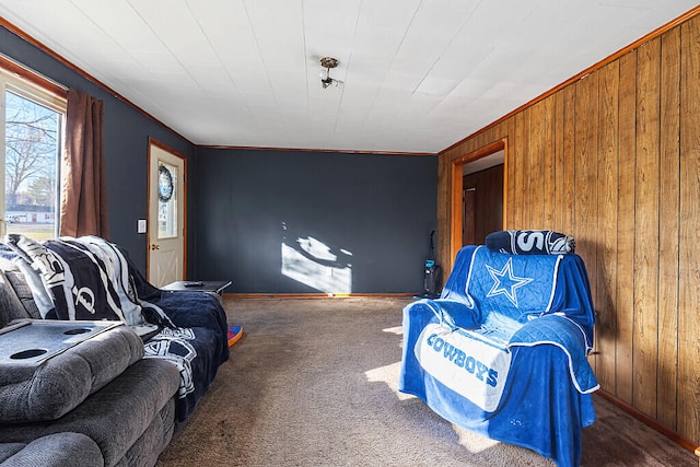 sitting room featuring carpet floors, wooden walls, and crown molding