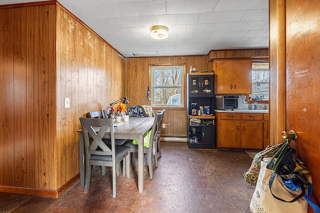 dining room featuring a baseboard heating unit and wood walls