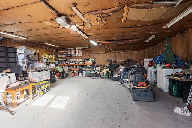 garage with a garage door opener, a workshop area, and separate washer and dryer