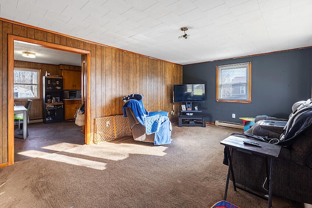 carpeted living room with wood walls, a baseboard heating unit, and ornamental molding