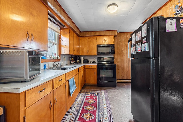 kitchen with wood walls, a baseboard radiator, black appliances, and sink