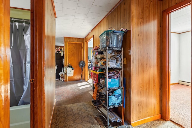 hall with wooden walls, light carpet, a baseboard heating unit, and crown molding