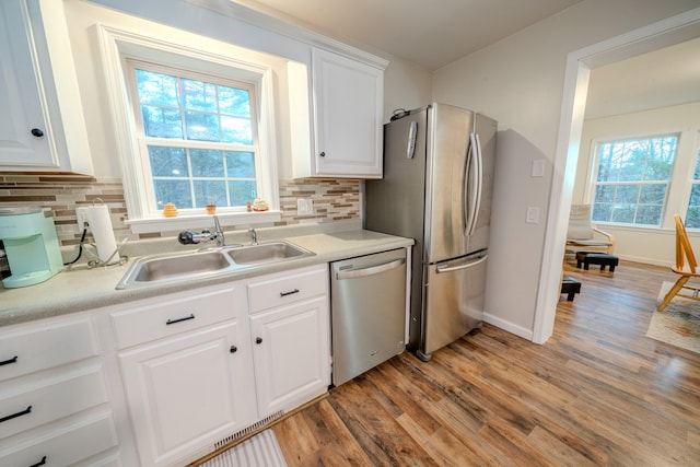 kitchen with decorative backsplash, white cabinets, light hardwood / wood-style floors, and appliances with stainless steel finishes