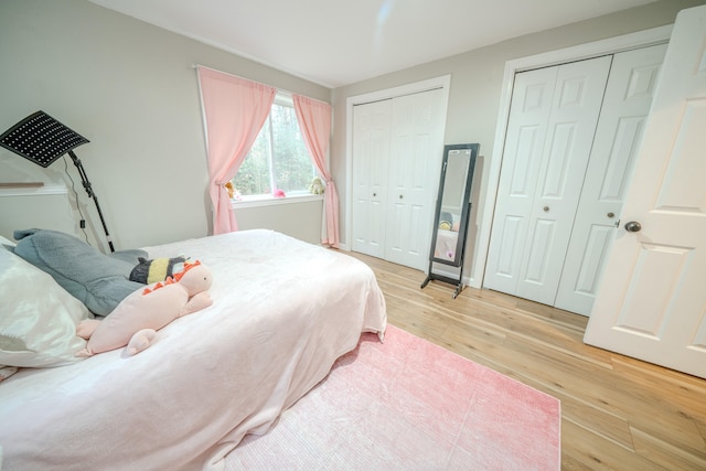 bedroom with light hardwood / wood-style flooring and multiple closets