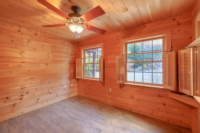 unfurnished room with hardwood / wood-style flooring, a wealth of natural light, and wooden walls