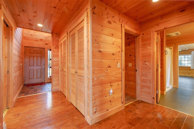 hall with hardwood / wood-style flooring, wood ceiling, and wooden walls