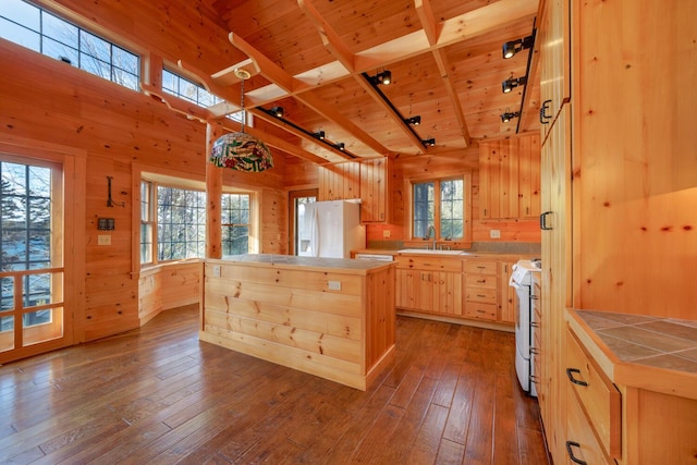 1700 Tremont Rd, Tremont, ME 04674 - kitchen featuring light brown cabinetry, tile countertops, wooden walls, white appliances, and a wood ceiling with exposed beams