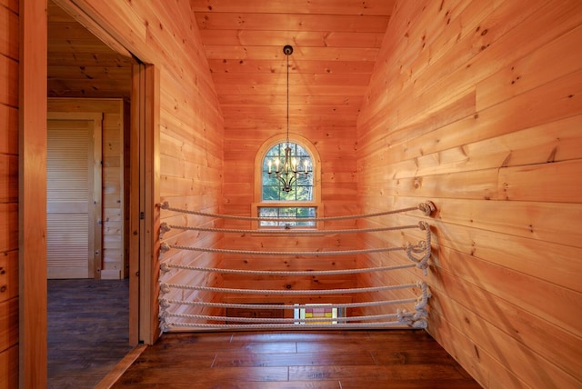 spare room featuring dark wood-type flooring, an inviting chandelier, wooden ceiling, lofted ceiling, and wood walls