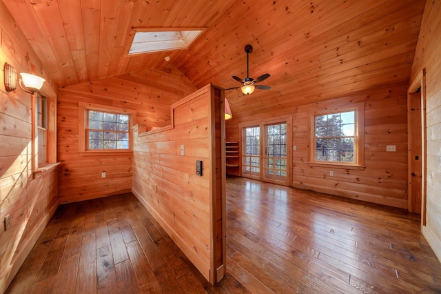 empty room with hardwood / wood-style floors, lofted ceiling with skylight, wooden ceiling, and wood walls