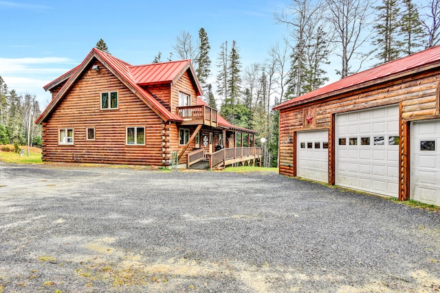 view of property exterior featuring a balcony, a garage, and a wooden deck