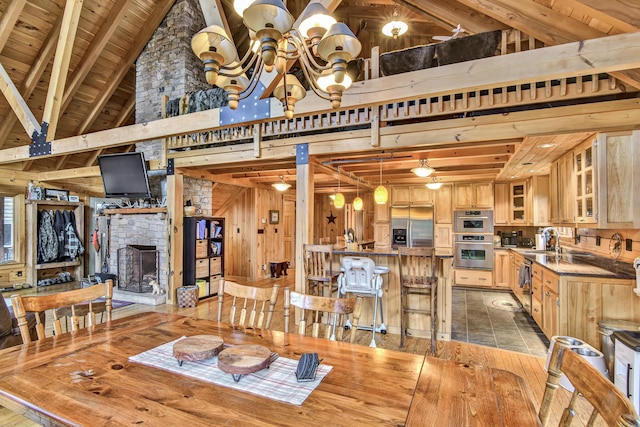 658 Mingo Loop Rd, Rangeley, ME 04970 - dining area featuring a chandelier, a fireplace, light wood-type flooring, wooden ceiling with exposed beams, and a high ceiling