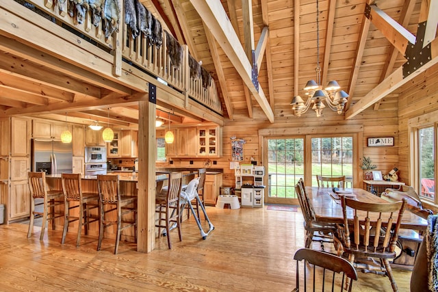 658 Mingo Loop Rd, Rangeley, ME 04970 - dining space featuring wooden ceiling with exposed beams, a chandelier, light wood-style flooring, wood walls, and high vaulted ceiling