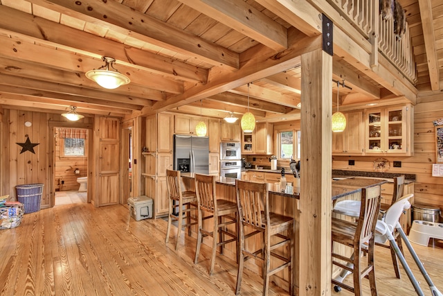 kitchen with kitchen peninsula, wooden walls, wooden ceiling, and light wood-type flooring