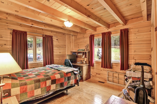 bedroom featuring beamed ceiling, light hardwood / wood-style flooring, wood ceiling, and wood walls