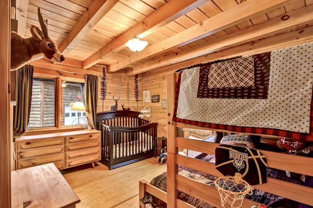 bedroom with wooden walls, beamed ceiling, light hardwood / wood-style floors, and wooden ceiling