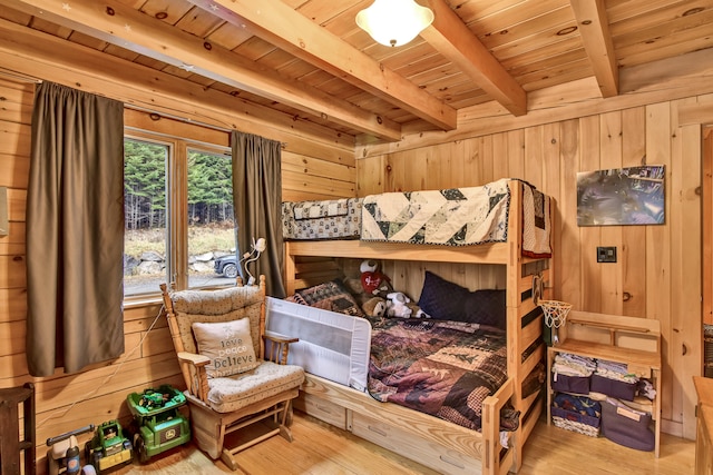 bedroom with beam ceiling, wood walls, hardwood / wood-style floors, and wood ceiling