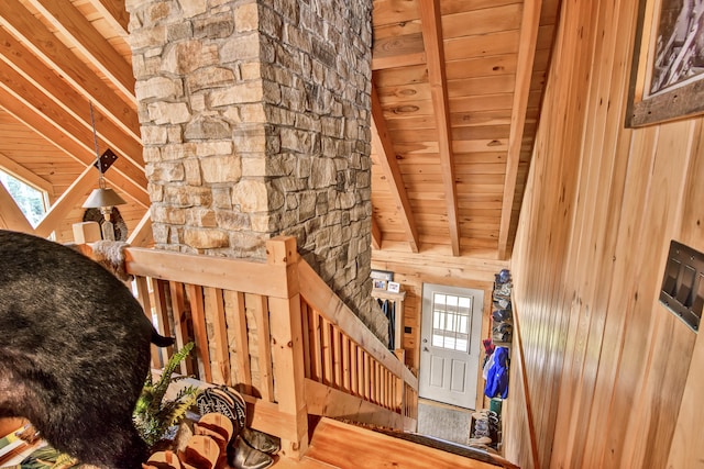 stairs featuring beam ceiling, wooden walls, a healthy amount of sunlight, and wood ceiling