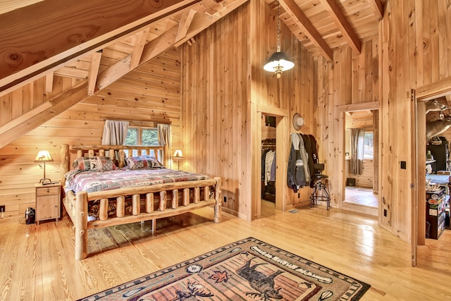 bedroom with hardwood / wood-style floors, lofted ceiling with beams, wood ceiling, and wooden walls