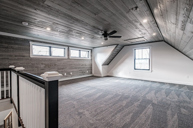 additional living space featuring wood walls, wooden ceiling, ceiling fan, dark carpet, and vaulted ceiling