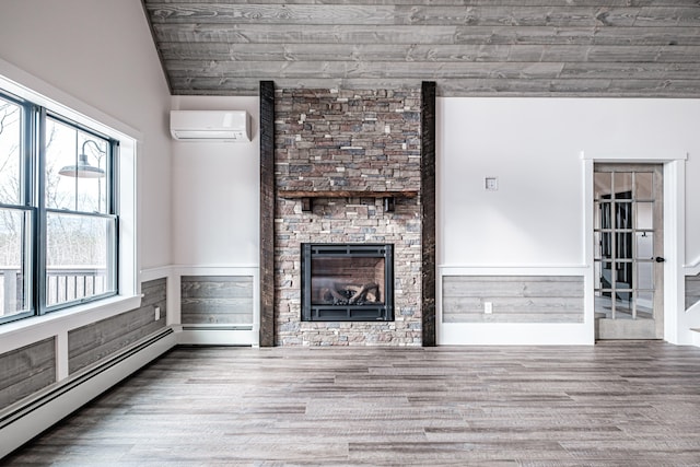 unfurnished living room with a baseboard heating unit, wood-type flooring, wood walls, a fireplace, and an AC wall unit