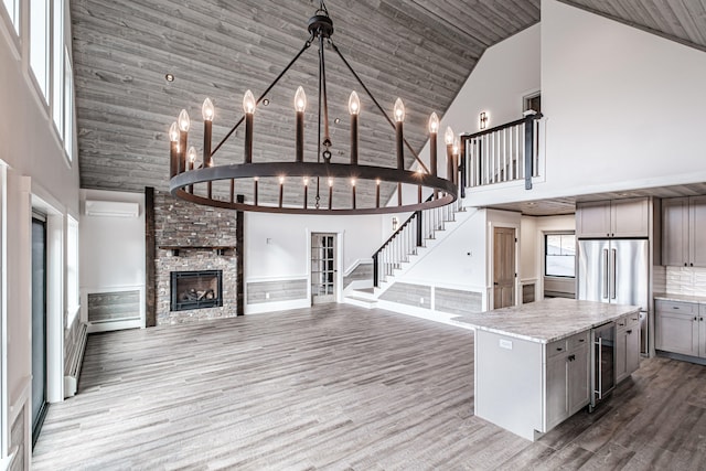 kitchen with wine cooler, a kitchen island, high vaulted ceiling, gray cabinets, and a large fireplace