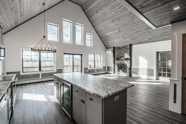 kitchen with wine cooler, decorative light fixtures, high vaulted ceiling, dark hardwood / wood-style flooring, and a large fireplace