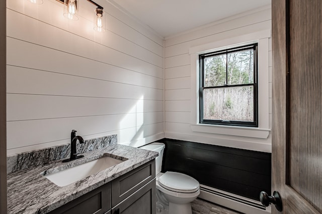 bathroom featuring a baseboard heating unit, toilet, wood walls, hardwood / wood-style flooring, and vanity