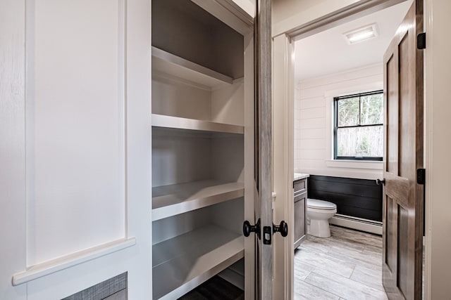 interior space featuring toilet, vanity, hardwood / wood-style flooring, and a baseboard heating unit