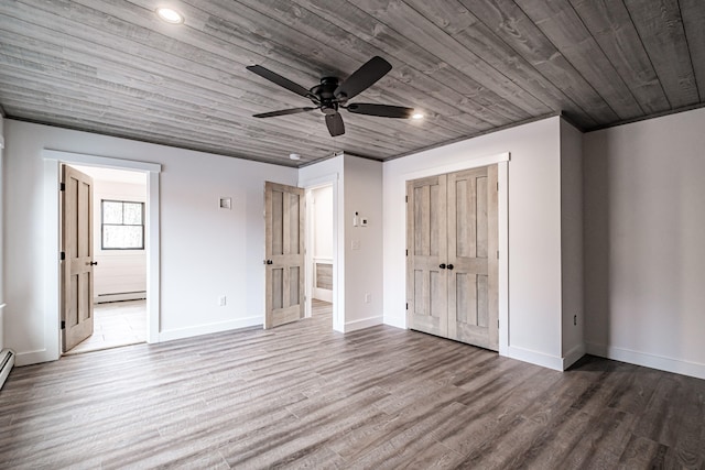 unfurnished bedroom featuring ensuite bathroom, hardwood / wood-style floors, baseboard heating, and ceiling fan