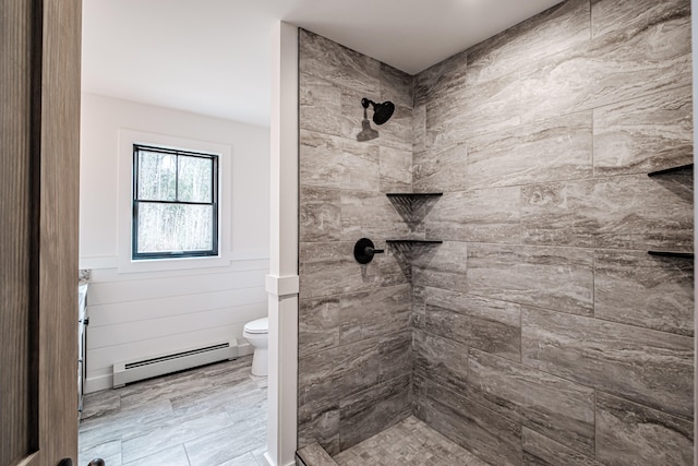 bathroom with toilet, a tile shower, and a baseboard heating unit