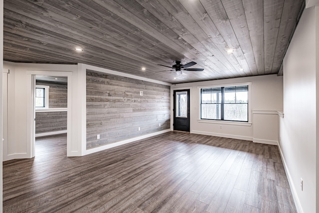 empty room with lofted ceiling, wood walls, wooden ceiling, dark hardwood / wood-style floors, and ceiling fan