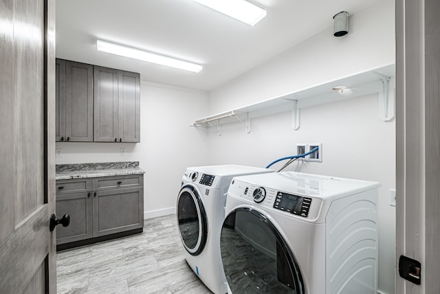 clothes washing area with cabinets and separate washer and dryer