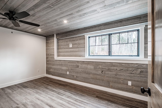 unfurnished room featuring hardwood / wood-style floors, wood walls, ceiling fan, and wooden ceiling