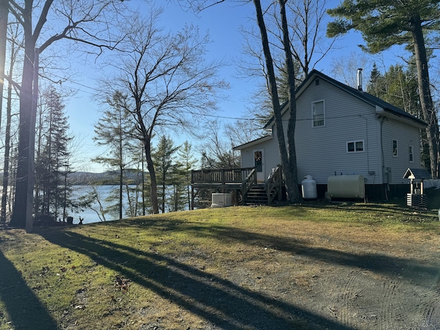 exterior space with a lawn and a deck with water view