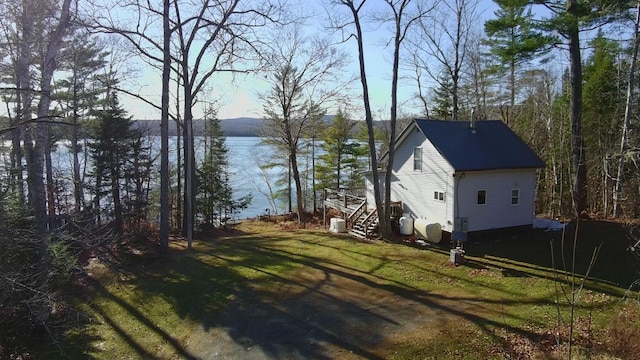 view of home's exterior with a water view and a lawn