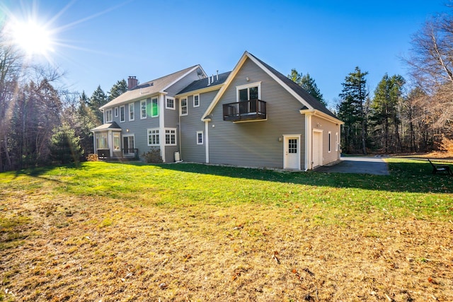 rear view of property featuring a balcony and a lawn