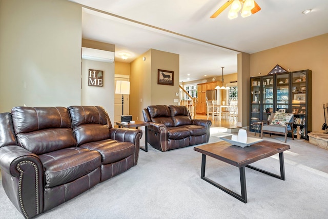 living room with ceiling fan with notable chandelier, an AC wall unit, and light carpet