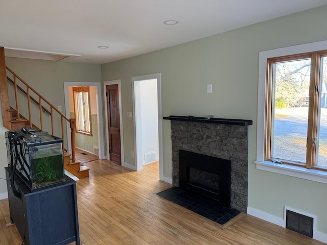 living room with hardwood / wood-style floors and a stone fireplace