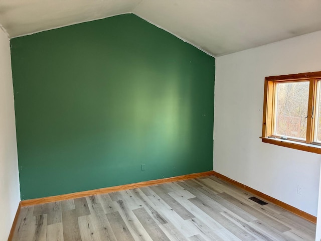 spare room featuring light hardwood / wood-style flooring and lofted ceiling