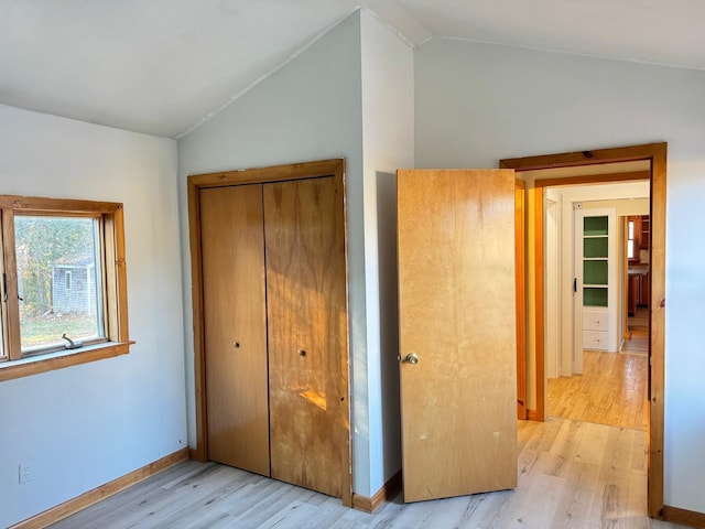 unfurnished bedroom featuring a closet, light hardwood / wood-style floors, and vaulted ceiling