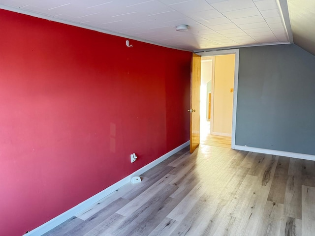 spare room featuring vaulted ceiling and light wood-type flooring