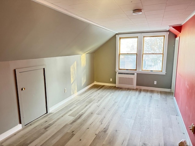 additional living space featuring light wood-type flooring, an AC wall unit, and vaulted ceiling